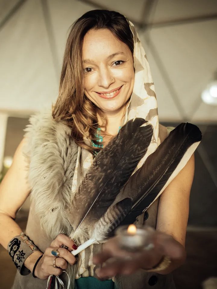 Photo of Anna Sundari in her yurt holding eagle feathers